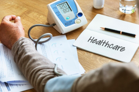 **Alt Text:** *Person using a digital blood pressure monitor at home, symbolizing self-care and hypertension management.*